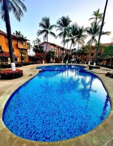 a large blue swimming pool with palm trees in the background at Villa Vacacionales Los Cayos Con Playa Privada in Boca de Aroa