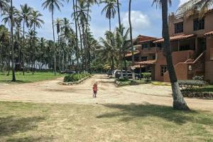 Mała dziewczynka stojąca na polnej drodze obok budynku w obiekcie Villa Vacacionales Los Cayos Con Playa Privada w mieście Boca de Aroa