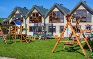 a house with wooden playground equipment in front of it at Cozy Home In Grzybowo With Kitchen in Grzybowo