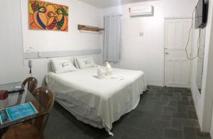 a bedroom with a white bed with a table and chairs at Casamar Pousada in Paulista