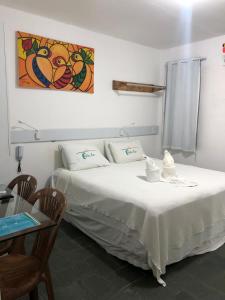 ein Schlafzimmer mit einem Bett, einem Tisch und einem Gemälde in der Unterkunft Casamar Pousada in Paulista
