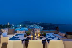 a patio with a table and chairs at night at Coat of Arms Mansion in Fira