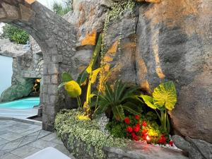 a garden with flowers in front of a rock wall at Rock House Villa in Ischia