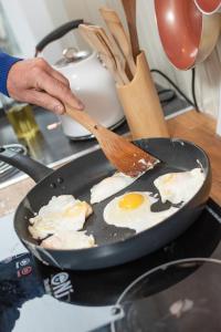 una persona que fríe huevos en una sartén con una espátula en Moffat Independent Hostel en Moffat
