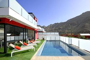 un edificio con piscina y tumbonas en Villa Morro del Guincho 31, en Mogán