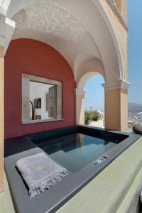 a swimming pool in a room with a red wall at Coat of Arms Mansion in Fira