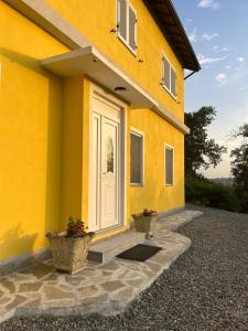 ein gelbes Haus mit zwei Topfpflanzen davor in der Unterkunft Villa Flora di Capriata d'orba in Predosa