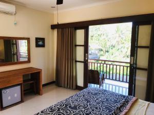 - une chambre avec un lit, une télévision et un balcon dans l'établissement Ayu Bisma Homestay, à Ubud