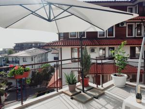 a white umbrella on a balcony with potted plants at La terrace Sea view in Sveti Vlas
