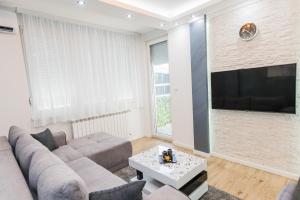 ein Wohnzimmer mit einem Sofa und einem Flachbild-TV in der Unterkunft JACUZZI LUX SANJA in Subotica