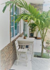 a porch with a white bench and a palm tree at Buritaca House in Buritaca