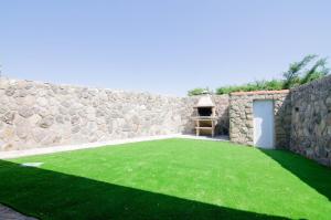 un mur en pierre avec une pelouse verte dans une cour dans l'établissement Casa rural Los Cántaros. Zarapicos, à Zarapicos