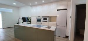 a kitchen with white cabinets and a white refrigerator at Alójate Gandia Ermita in Gandía