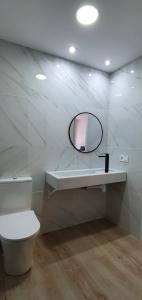 Alójate Gandia Ermita في غانديا: حمام أبيض مع مرآة ومرحاض