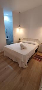 Cette chambre comprend un grand lit blanc et du parquet. dans l'établissement Alójate Gandia Ermita, à Gandía