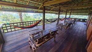 Bukit Lawang Hill Resort في بوكيت لاوانج: شرفة مع مقاعد وأراجيح على سطح خشبي