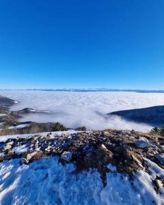 una pila de nieve en la cima de una montaña con nubes en Logements au dessus du Bois de l Ours Les Rousses en Les Rousses