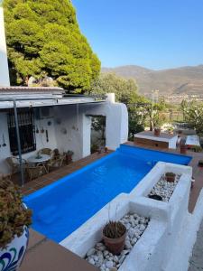 une maison avec une piscine bleue sur une terrasse dans l'établissement Huerta La Niña Arenas, à Órgiva