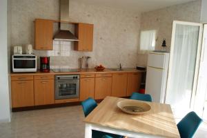 una cocina con armarios de madera y una mesa con sillas azules en Vue sur mer - Appartement Les Pins, 