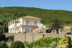 una casa en una colina con una palmera en Vue sur mer - Appartement Les Pins, 