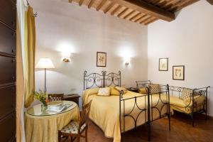 1 Schlafzimmer mit 2 Betten, einem Tisch und Stühlen in der Unterkunft Il Poggio degli Olivi in Bettona
