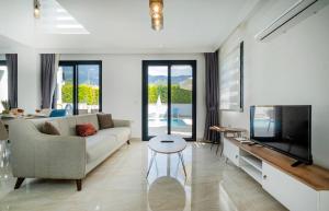 a living room with a couch and a tv at Modern chic 4-bedroom villa with private pool and garden in central Hisaronu in Fethiye
