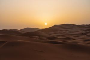 een zonsondergang in de woestijn boven de duinen van de Theukong woestijn bij Mhamid camp activités in Mhamid