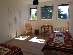 a bedroom with two beds and a table and two chairs at Villa sur la corniche vue mer in Concarneau