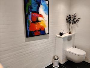 a bathroom with a toilet and a painting on the wall at Værelser i midtbyen in Herning