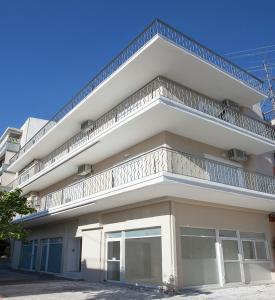 - un bâtiment blanc avec un balcon au-dessus dans l'établissement Διαμερίσματα στο Δυτικό Μοσχάτο, au Pirée