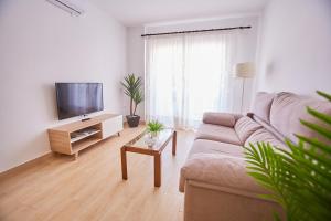 sala de estar con sofá y TV de pantalla plana en VistAzul 402, en Lepe