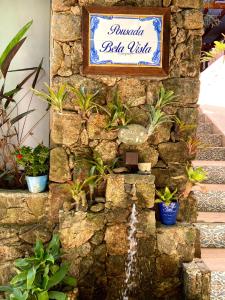 un panneau sur un mur en pierre avec une fontaine dans l'établissement Pousada Bela Vista, à Abraão