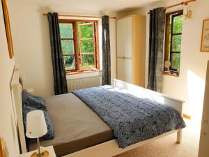 ein Schlafzimmer mit einem Bett und zwei Fenstern in der Unterkunft Ferienwohnung Hyggebo in Langballig