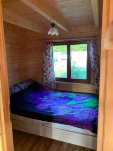 łóżko w drewnianym domku z oknem w obiekcie Domki u Wiesi w mieście Giżycko
