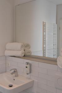 a bathroom with a sink and a mirror and towels at Landhaus Hamester - Hotel & Restaurant - neu eröffnet September 2022 in Basthorst
