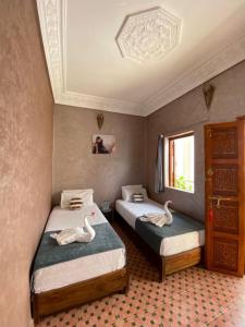 2 Betten in einem Zimmer mit Schwänen darauf in der Unterkunft Dar Dikrayat in Marrakesch