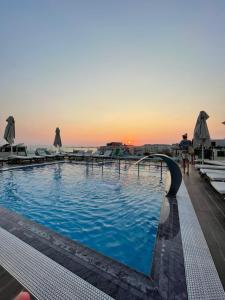 a swimming pool with a sunset in the background at Hotel Empire Albania in Durrës