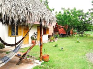 Cabanas Rusticas في لاس بينيتاس: أرجوحة أمام منزل مع سقف من العشب