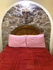 un letto con una croce sopra un muro di pietra di La Capilla Apartment In ExHacienda La Escalera a Guanajuato