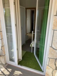 przesuwane szklane drzwi pokoju z zieloną zasłoną w obiekcie Villa Androcec w mieście Žgaljić
