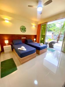 a bedroom with two beds and a large window at Sands Grand Hotel in Dhigurah