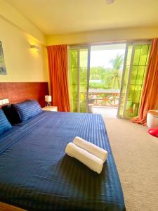 a bedroom with a blue bed with two towels on it at Sands Grand Hotel in Dhigurah
