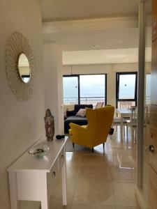 a living room with a table and a yellow chair at Vivienda adosada en Castillo, Caleta de Fuste in Caleta De Fuste