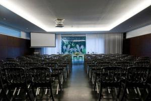 a conference room with chairs and a white screen at Paredes Design Hotel in Paredes