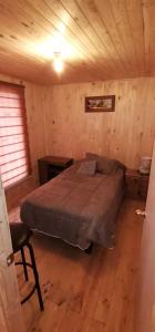 1 dormitorio con 1 cama en una cabaña de madera en Cabaña La campana, en Hijuelas
