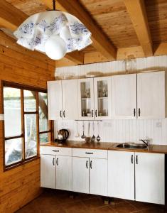 una cocina con armarios blancos y una lámpara de araña en Chalupa Trucovna 