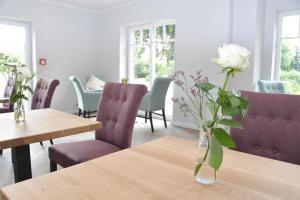 a vase with a white rose sitting on a table at Landhaus Hamester - Hotel & Restaurant in Basthorst