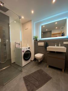 a bathroom with a shower toilet and a washing machine at MOREHOME-Apartments in Mindelheim