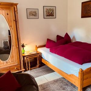 1 dormitorio con cama con almohadas rojas y espejo en Gästehaus Peerhus Dönsel - Peerknecht en Rehden