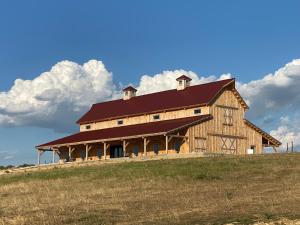 a large wooden barn with a red roof on a hill at Blue Hills Ranch in McGregor